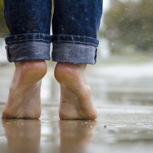 a person standing outside barefoot in the rain