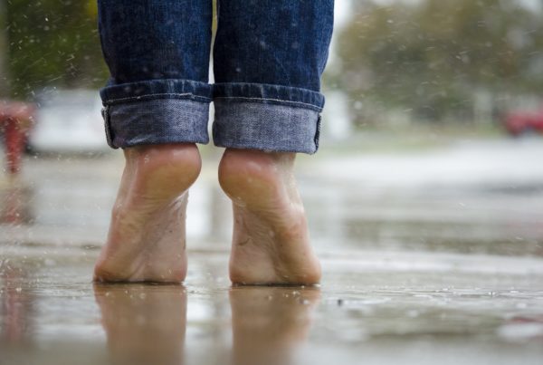a person standing outside barefoot in the rain